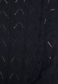 Tejido de punto negro que presenta un patrón texturizado de formas de diamante con detalles de calado. Textura suave y transirable.