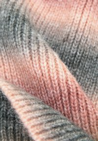 Dzianina o gradiencie miękkiego różu i szarości; charakteryzuje się gładką fakturą i delikatnym, ukośnym żebrowaniem.