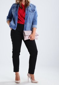 Veste en denim, haut rouge, pantalon noir ajusté, pochette rose clair et escarpins nude. Comprend des poches avant et des détails de boutons sur la veste.
