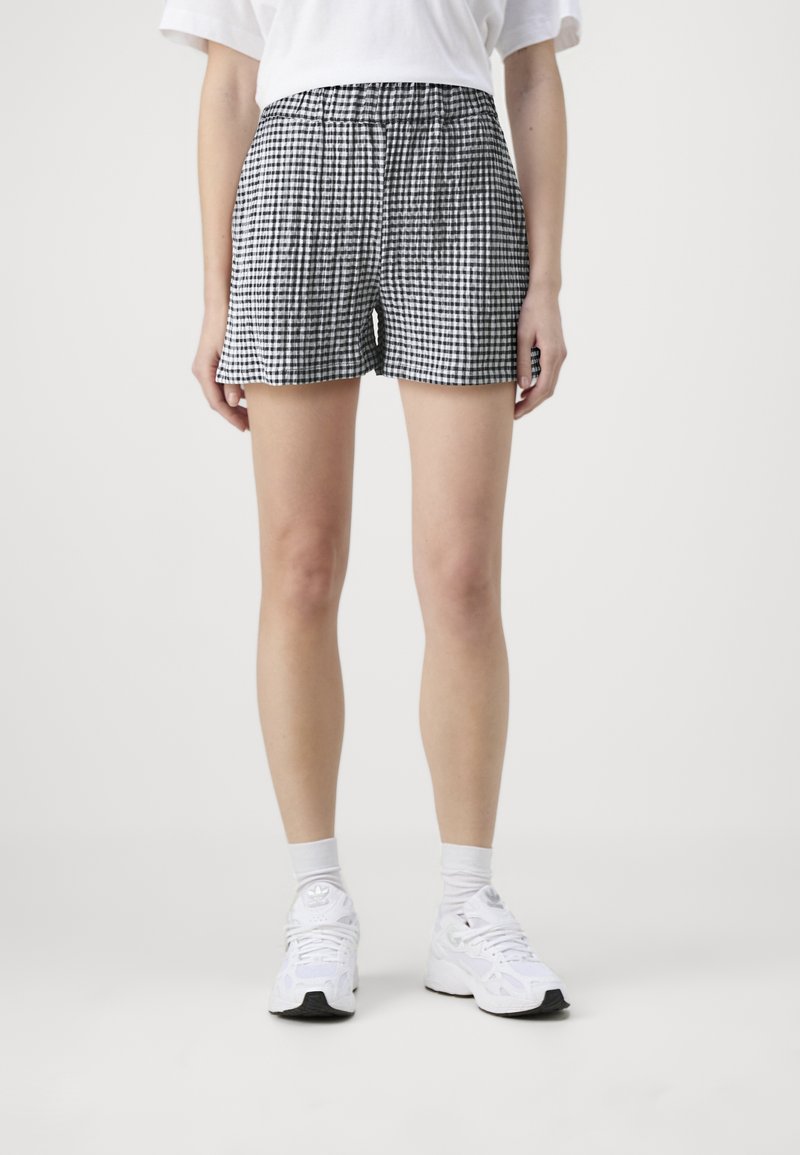 Shorts à carreaux noir et blanc avec une taille élastique, fabriqués dans un tissu léger, offrant une coupe décontractée et un ourlet plat.