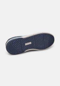 Talpa de sneaker albastru închis cu un model hexagonal, având material din cauciuc, zone texturate și un accent alb lângă călcâi, etichetat "Bata."