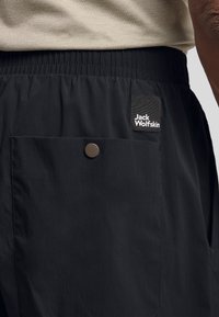 Pantaloni corti neri realizzati in un tessuto leggero e testurizzato. Dotati di una vita elasticizzata, tasche laterali e un'etichetta di marca sul davanti.