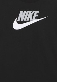 Camiseta de algodón negra con un gran logo de Nike en blanco y gris en el pecho. Cuello redondo y mangas cortas. Textura suave.
