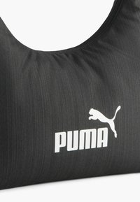 Borsa nera in tessuto con una texture liscia, caratterizzata da un prominente logo Puma bianco e un design elegante e arrotondato.