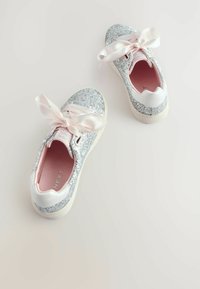Baskets argentées scintillantes avec une tige pailletée, des nœuds en satin blanc et une semelle intérieure rose. Bout arrondi et semelle texturée rembourrée.