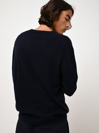 Marineblauer Pullover aus weichem Material mit lässigem Schnitt, Rundhalsausschnitt und geripptem Saum. Die Rückansicht zeigt minimale Details.