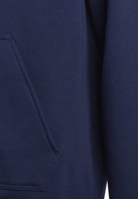 Primo piano di tessuto blu navy con una tasca cucita e dettagli di cuciture visibili su un indumento.