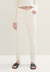 Vita denimjeans med hög midja, rak benform och fransad fåll. Kombinerat med svarta slip-on sandaler. Lätt, texturerat tyg.