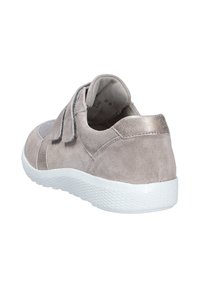 Sneaker en suède gris clair avec une semelle en caoutchouc blanc, dotée d'une sangle à boucle et d'un accent métallique au talon. Forme arrondie.