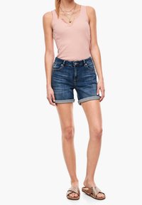 Top sans manches rose clair, short en denim bleu avec ourlets roulés et sandales à glissière à motifs marron. Design simple et coupe décontractée.