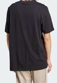 Camiseta de algodón negra con mangas cortas, escote redondo y un corte relajado. La tela tiene una textura suave y un diseño simple.