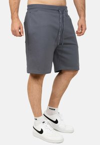 Grijze sportieve shorts gemaakt van zachte stof, met een elastische tailleband met trekkoord, zijzakken en een relaxte pasvorm.