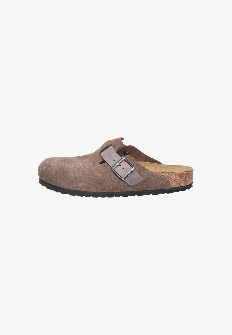 Brown suede clog with a wide toe box, adjustable gray strap with buckle, cork footbed, and textured black rubber sole.