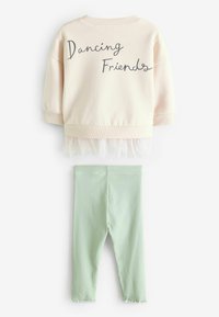 Vaaleanpunainen huppari, jossa on tummalla tekstillä "Dancing Friends", yhdistetty ribatuille mintunvihreille legginsseille. Hupparissa on tylli-reunus.