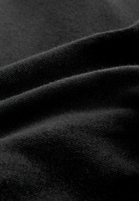 Tissu noir présentant une surface douce et texturée avec des plis subtils et une apparence lisse, mettant en valeur le tissage fin du matériau.