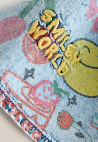 Tkanina dżinsowa z kolorową haftem. Główne elementy wizualne to napis "SMILEY WORLD" w żółtym kolorze, truskawki, kwiaty oraz uśmiechnięta buźka.