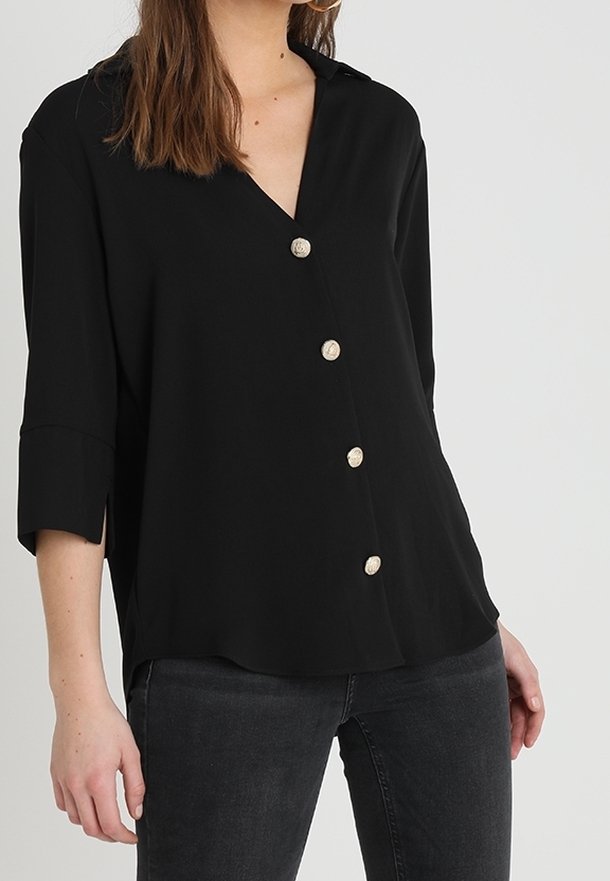 Svart blus med v-ringning och trekvartsärmar, prydd med fyra gyllene dekorativa knappar framtill, i ett mjukt tyg och avslappnad passform.
