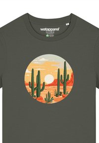 Olijfgroene t-shirt met een cirkelvormig zonsondergangontwerp met cactussen, bergen en een zon op een oranje en blauwe achtergrond.