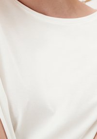 Bílý, lehký bavlněný top se širokým výstřihem a krátkými rukávy. Hladká textura s minimem švů. Neformální design.