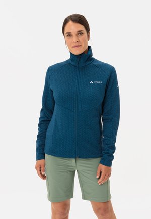 Blue patterned fleece jacket with high collar, full zip closure, and fitted design, paired with green shorts.