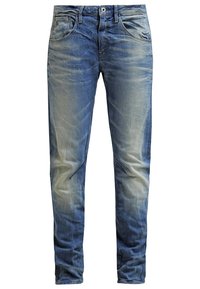 Mörkblå denimjeans med en blekt tvätt, fem fickor, bältesöglor och dragkedja. Tyget visar på lätt veck och variation i textur.