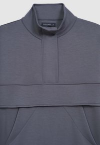 Pullover grigio con colletto alto, design a strati e tessuto testurizzato. Include un'etichetta con il nome del marchio "CALLIOPE."