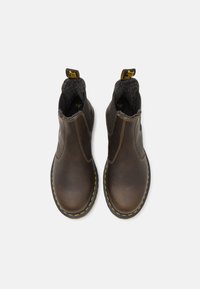 Brune læder ankelstøvler har elastiske sidepaneler, en struktureret indvendig foring og en gul stikning som accent langs den sorte sål.