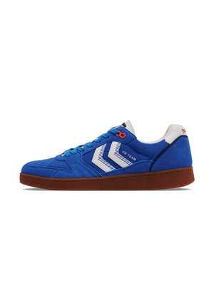 Blå semsket sneakers med røde detaljer og hvite diagonale striper. Har gummisåle og snøring. Merkenavnet på hælen.