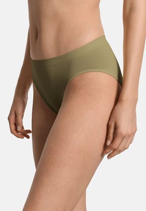 Mujer con braga alta sin costuras de color verde oliva, mostrada desde la cintura hasta la parte superior del muslo sobre un fondo liso.