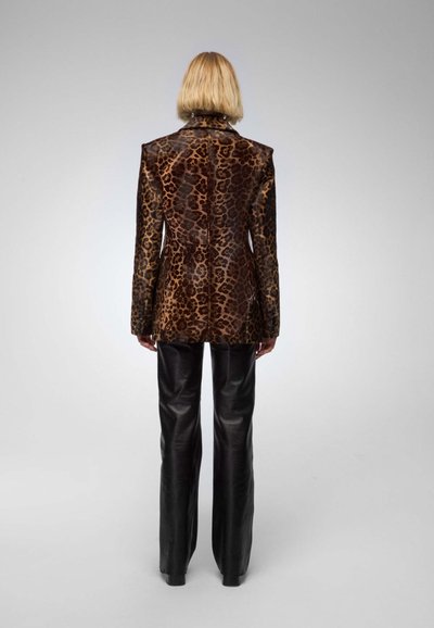 Leopard print velvet blazer with a structured design, featuring sharp shoulders and long sleeves, paired with high-waisted black leather pants.