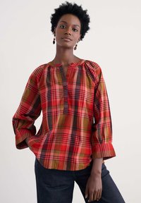 Czerwona koszula w kratę z długim rękawem, z zapięciem na guziki, marszczeniami i podwiniętymi mankietami, wykonana z lekkiego materiału.