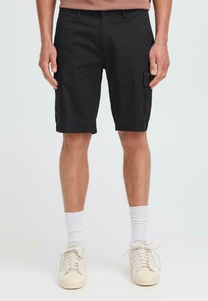Black cargo shorts made of cotton. Features include two side pockets, a waistband with belt loops, and a straight cut. Paired with white socks and sneakers.