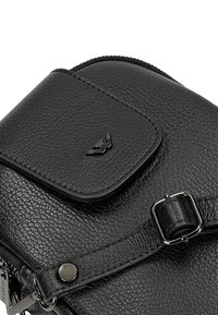 Schwarze Umhängetasche aus genarbtem Leder mit vorderer Klappentasche, silberner Schnalle und kleinem Metalllogo auf der Taschenklappe.