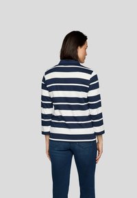 Marineblau- und weiße gestreifte Langarm-Polohemd mit Kragen, hat eine lässige Passform und eine weiche Textur, getragen mit blauen Jeans.