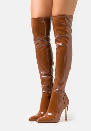 Brown over-the-knee boots made of glossy material, featuring a pointed toe and a high stiletto heel, with a side zipper detail.