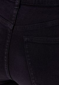 Svart denimjeans med en mjuk textur, som har bakfickor, subtila sömmar och en figurnära design. Tyget är något elastiskt.