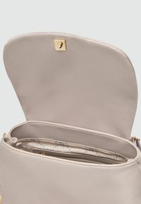 Sac à main beige avec une texture lisse, doté d'une fermeture à pression en or. L'intérieur possède une doublure à motifs et une poche zippée.