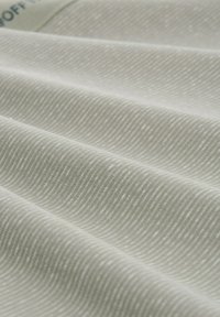 Tessuto grigio chiaro con una texture, caratterizzato da un sottile motivo ondulato, che mostra molteplici pieghe e una consistenza superficiale liscia.