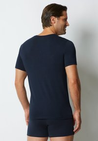 Navy blue short-sleeve t-shirt, fitted design, smooth texture, crew neckline, paired with navy boxer shorts, viewed from the back.