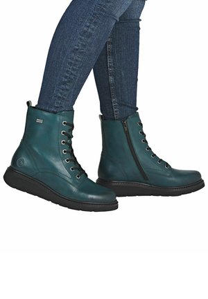 Botas de tobillo de cuero verde azulado con cordones negros y cremallera lateral, que cuentan con una suela texturada para mayor agarre. Acabado suave con acentos mínimos.