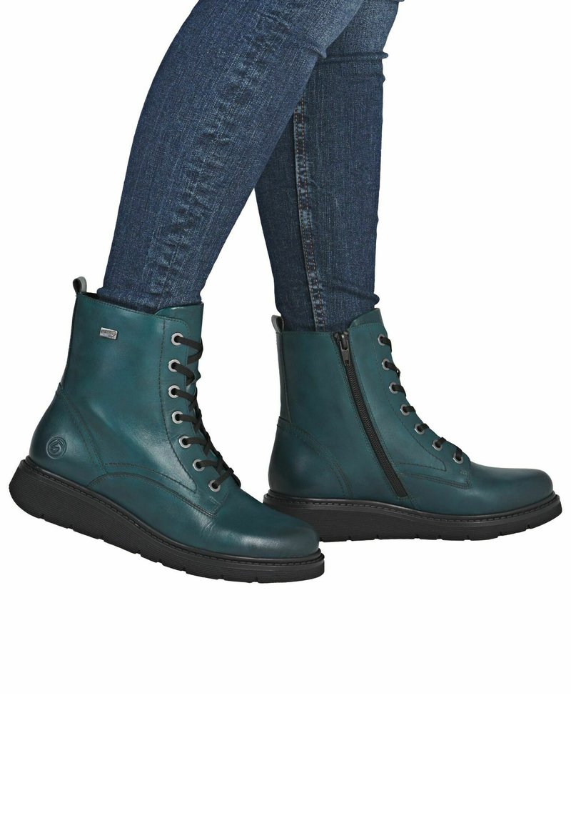 Botas de tobillo de cuero verde azulado con cordones negros y cremallera lateral, que cuentan con una suela texturada para mayor agarre. Acabado suave con acentos mínimos.