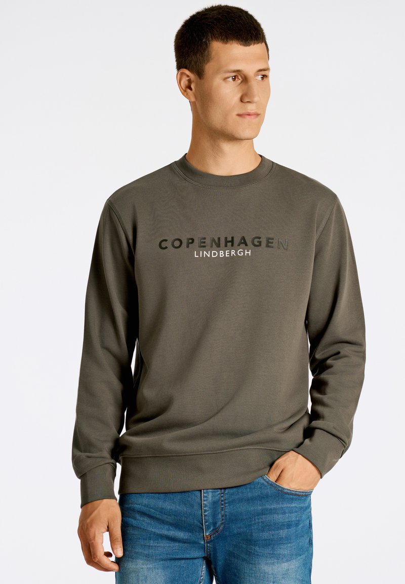 Sudadera verde oliva con cuello barco, que presenta el texto "Copenhague Lindbergh" en negro contrastante. Textura suave con puños acanalados.