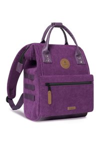 Purple corduroy backpack with leather accents, top handles, adjustable straps, front zipper pocket, and a circular logo patch.