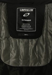 Sort ydertøj med en struktureret inderside, der har et mærke med teksten "CARISMA," "OUTERWEAR" og størrelse "SMALL."