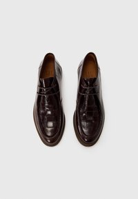 Dunkelbraune Lederschuhe mit gewebter Textur an der Vorderseite, Schnürdesign, runder Zehenform und kontrastierender Gummisohle.
