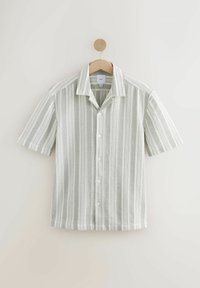 Camisa de manga corta con rayas verticales en verde claro y blanco. Frontal abotonado, cuello puntiagudo, tejido texturizado. Cuelga en un perchero de madera.