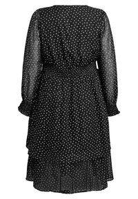 Melna kleita ar garām caurspīdīgām piedurknēm, šāvu vidukli, vairāku slāņu ruffles apakšmalu un izkaisītām baltām punktiņām visā kleitā, izgatavota no viegla auduma.