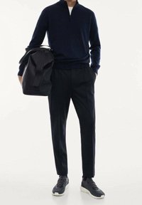 Námořnický svetřík se zipem do čtvrtiny, upravené černé kalhoty a černé tenisky. Černá taška s dvěma uchy. Elegantní, moderní silueta.