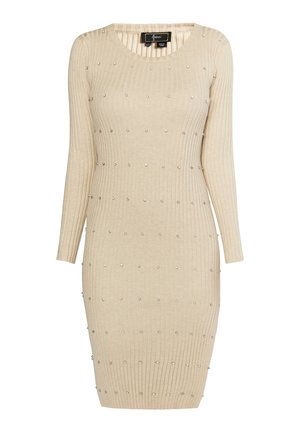 Hladké béžové šaty s dlouhými rukávy, do délky ke kolenům, zdobené stříbrnými cvočky uspořádanými do tečkovaného vzoru po celém materiálu.