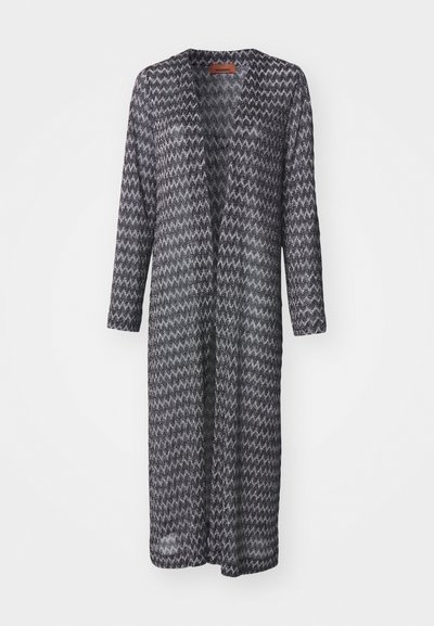 Pitkä, avonainen kardigan mustavalkoisella siksak-kuviolla, valmistettu kevyestä, puoliksi läpinäkyvästä kankaasta, jossa on pitkät hihat eikä kiinnitysmekanismeja.